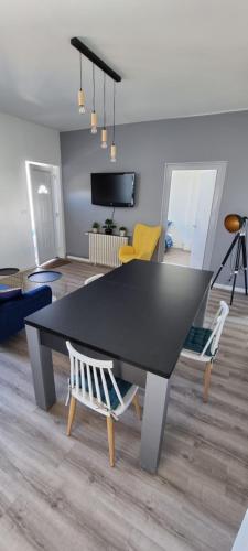 - une table et des chaises noires dans le salon dans l'établissement Sadi Carnot Appartement, à Dijon