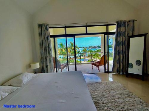 a bedroom with a large bed and a large window at Grand Baie Villa des amis sur la plage. in Grand Baie