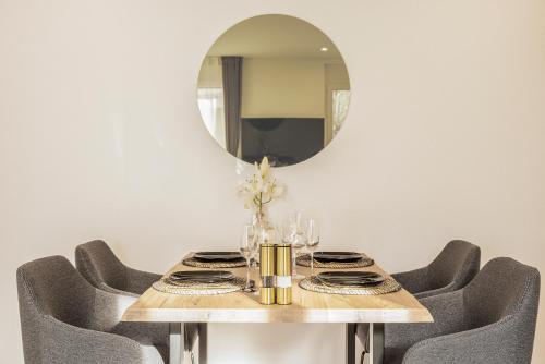 a dining room table with chairs and a mirror at St Georgen-Strasse Studios by VISIMO - Design, City, Nature in St. Gallen