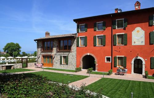 a large red brick building with a yard at Residence Borgo Mondragon in Lazise