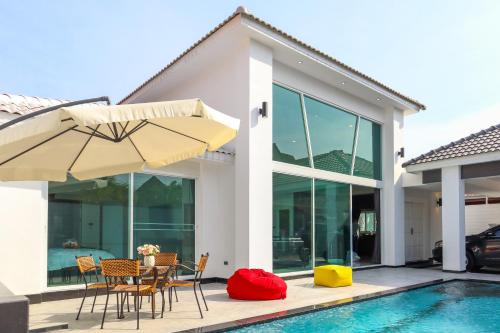 a house with a pool and a patio with chairs and an umbrella at *City~house* 芭堤雅豪华泳池别墅近步行街 in Pattaya South