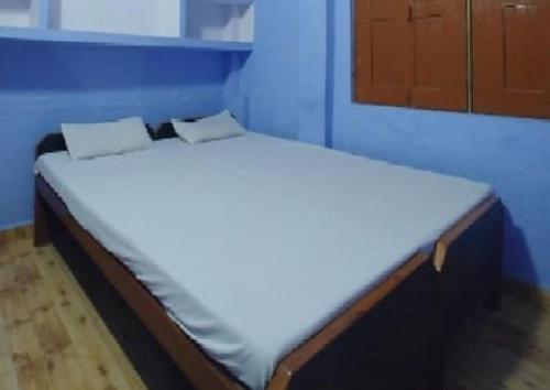 a bed in a room with a blue wall at Krishna Guest House By WB Inn in Agra