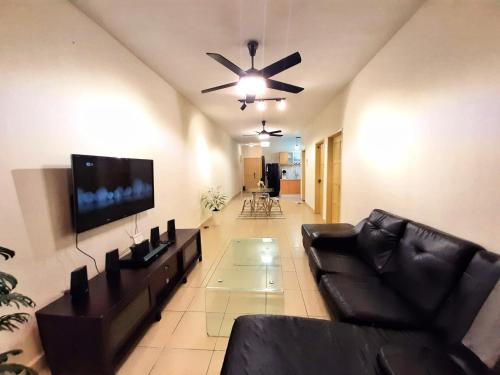 a living room with a black couch and a flat screen tv at N'dnie Homestay Pelangi Mall Condominium in Kota Bharu