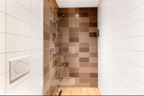 a shower stall in a bathroom with white tiles at U Parkhotel in Enschede