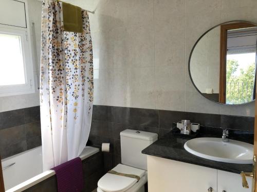 een badkamer met een wastafel, een toilet en een spiegel bij Villa Rosa in Begur