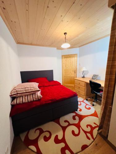 - une chambre avec un lit rouge et un bureau dans l'établissement Ferienwohnung Zeppelin, à Château-d'Oex