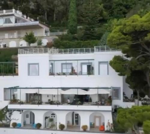 Une grande maison blanche avec des personnes sur le balcon dans l'établissement VILLA OLGA LUXURY CAPRI, à Capri