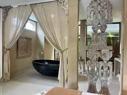 a bathroom with a black tub and a window at Chakra Living Ubud in Ubud