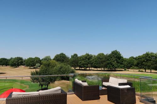 a balcony with wicker furniture and a golf course at Bicester Hotel, Golf & Spa in Bicester