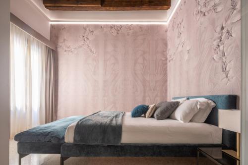 a bedroom with a bed with a pink wall at Ninfea Luxury Suites in Venice