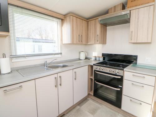 a kitchen with white cabinets and a stove top oven at 17 Summer Meadows in Ashington