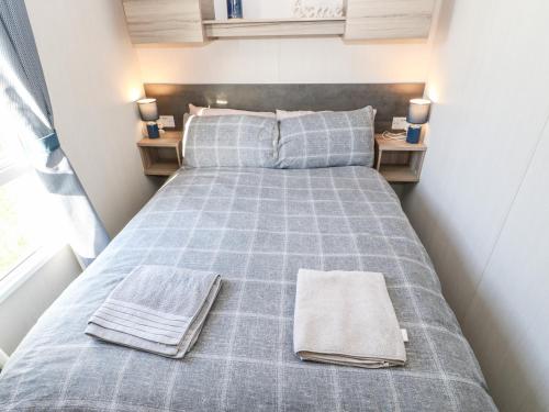 un letto in una piccola stanza con due asciugamani di 17 Summer Meadows a Ashington