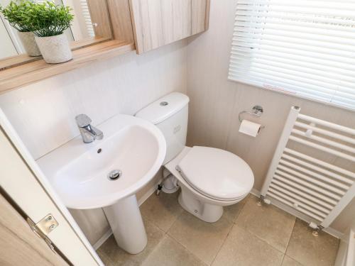 La salle de bains est pourvue de toilettes blanches et d'un lavabo. dans l'établissement 17 Summer Meadows, à Ashington