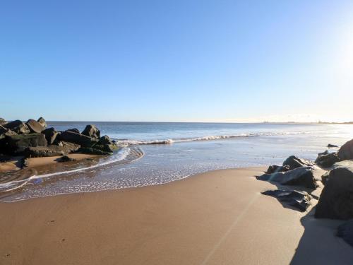 a sandy beach with rocks and the ocean at 17 Summer Meadows in Ashington