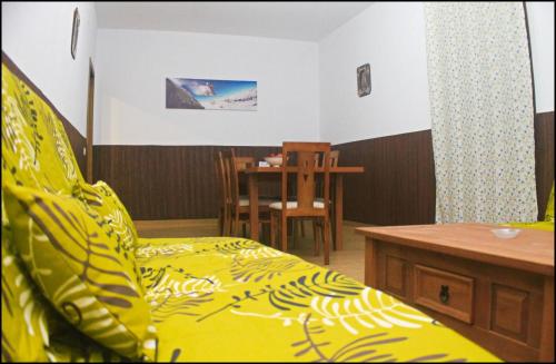 Un dormitorio con una cama amarilla y una mesa en Casa Maestro Roche, en Roche
