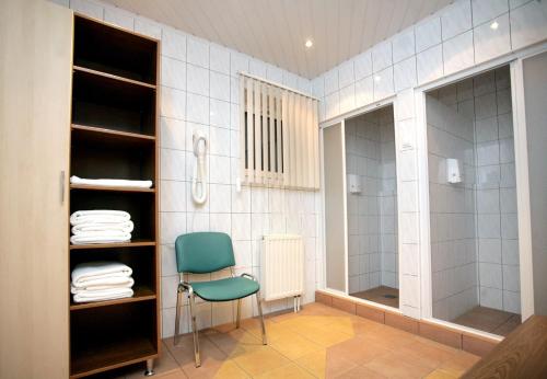 La salle de bains est pourvue d'une douche, d'une chaise et de serviettes. dans l'établissement Hotel Pasymowski, à Mława