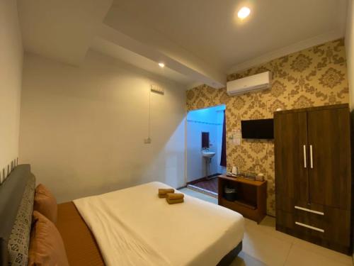 um quarto com uma cama e uma televisão em MJ inn em Ranau