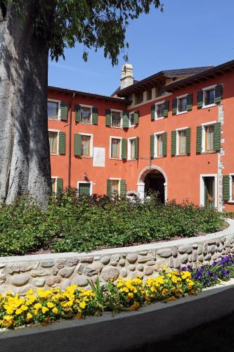 a building with a tree and flowers in front of it at Residence Borgo Mondragon in Lazise