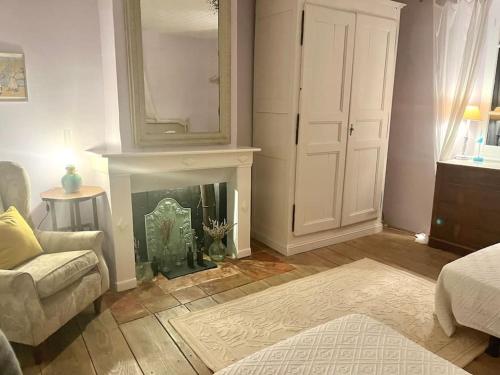 a living room with a fireplace and a mirror at La Maison de Mama C: Charming french village home in Sainte-Colombe-sur-lʼHers