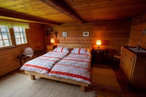 um quarto com uma cama num chalé de madeira em Ferienhaus Fromsenrüti em Walzenhausen