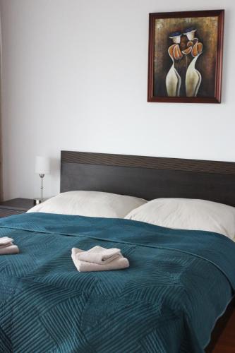 ein Bett mit einer blauen Decke mit zwei Handtüchern darauf in der Unterkunft OK Apartament Uzdrowiskowa in Świnoujście