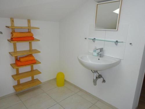 a bathroom with a sink and a shelf with towels at Rehalp Westen in Bischofszell