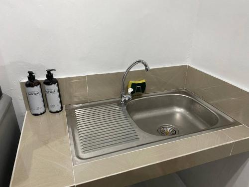 a kitchen sink with a faucet and two bottles at The Tiny Room Apartment Units near Anonas and Cubao in Manila