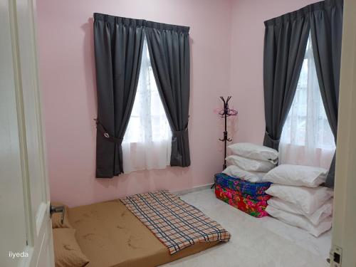 Habitación con 2 ventanas, cortinas negras y colchón. en Warisan Qaseh Homestay en Tanah Merah