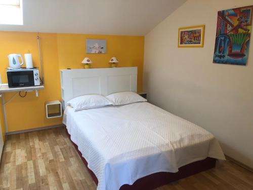 a bedroom with a white bed and a microwave at Studio Neven with Sea View in Baška
