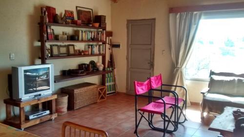 a living room with pink chairs and a television at El Chaparral in Potrero de Garay