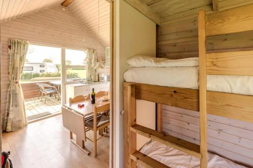 a bedroom with a bunk bed and a desk and a kitchen at First Camp Bogense Strand Camping & Cottages in Bogense