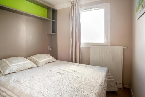 a bedroom with a bed with two pillows and a window at Le Drakkar in Courseulles-sur-Mer