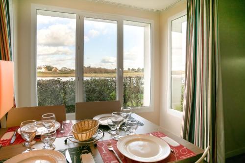 une table à manger avec des assiettes et des verres ainsi qu'une fenêtre dans l'établissement Le Drakkar, à Courseulles-sur-Mer