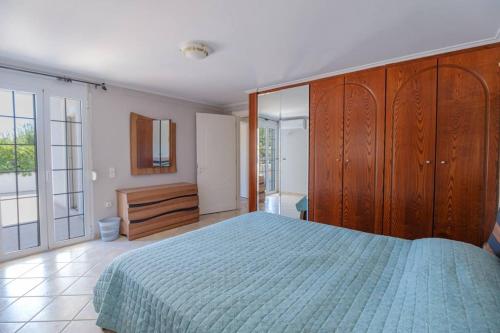 a bedroom with a blue bed and a wooden cabinet at Lefkathia Beach Villa - Gated Beach-Front Private Villa at Lefkathia Beach, Chios! in Volissos