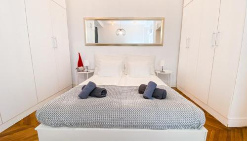 a white bedroom with a large bed with blue pillows at City Centre Synagogue Residential Apartment Budapest in Budapest