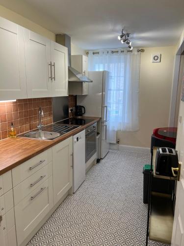 a kitchen with white cabinets and a sink at Glastonbury High Street Sanctuary- 2 BD, Sleeps 4 in Glastonbury
