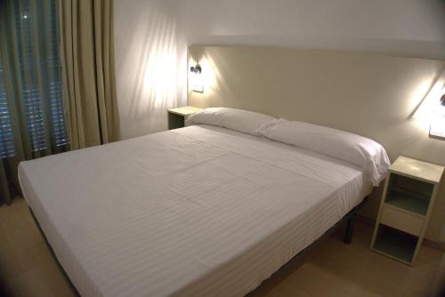 1 dormitorio con 1 cama blanca y 2 mesitas de noche en Apartaments Sant Jordi Fontanella, en Barcelona