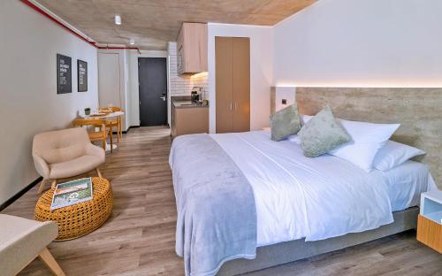 um quarto com uma cama grande, uma cadeira e uma mesa em hUB Providencia em Santiago