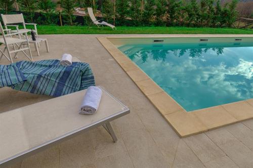 ein Pool mit einer Bank und Handtüchern darauf in der Unterkunft Villa Cristina modern farmhouse with Private Pool in Monsagrati