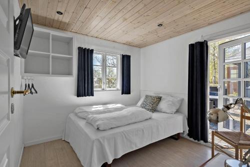 a white room with a bed and a window at First Camp Bøsøre Strand Feriepark in Hesselager