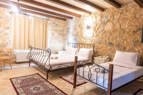 two beds in a room with a stone wall at Lithea mountain resort and spa in Florina