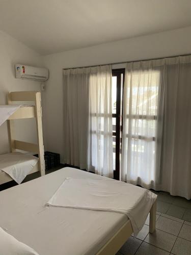 1 dormitorio con 1 cama y una ventana con cortinas en Duplex Residencial Santos, en Florianópolis