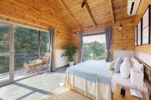 卡尔贾特Anjee's Chalet by StayVista - Mountain-view villa with Classic wooden interiors, Lush lawn & Snooker table的一间带床和大窗户的卧室