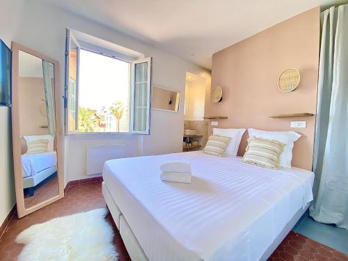 a large white bed in a room with a window at Sablettes Beach-plage-vue mer-centre ville in Menton