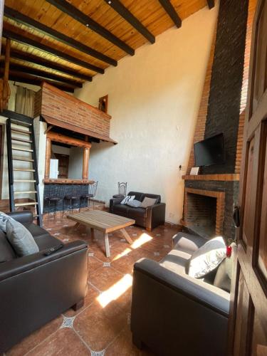 ein Wohnzimmer mit Sofas, einem Tisch und einem Kamin in der Unterkunft DNellys/Pinguica 1 in Mazamitla