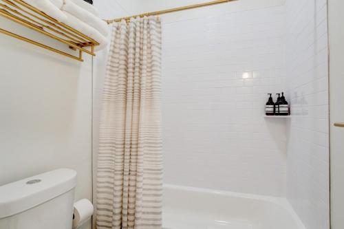 uma casa de banho branca com uma cortina de chuveiro e um WC. em Suite 1 Historic Art City Inn em Springville