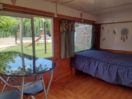 Habitación con cama y mesa de cristal. en DORMIS P/2 en Luján de Cuyo