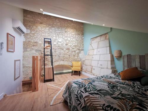 1 dormitorio con cama y pared de piedra en Maison 2-3 pers Angers-Saumur, en Louresse-Rochemenier