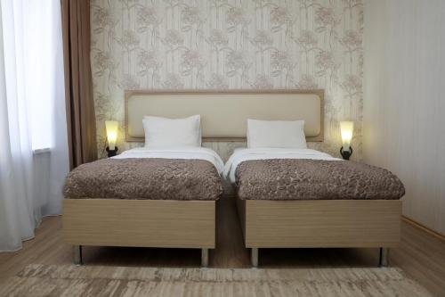 two twin beds in a room with two lamps at Rustaveli Palace in Tbilisi City