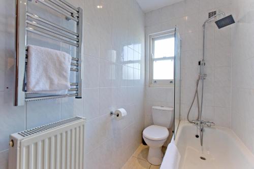 a white bathroom with a toilet and a bath tub at Calabria 3 - Spacious apartment in London